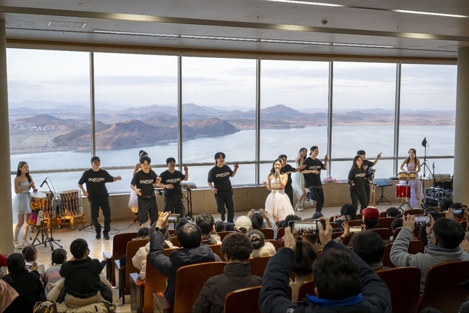 애기봉평화생태공원에서 반 고흐를 주요테마로 한 새해 첫 야간 특별문화예술행사 '愛기봉 별이 빛나는 밤에'가 개최돼 많은 관람객들 의 북녘을 등지고 공연하는 모습을 자신의 폰에 담고 있다. (사진=김포시 관광진흥팀 제공)