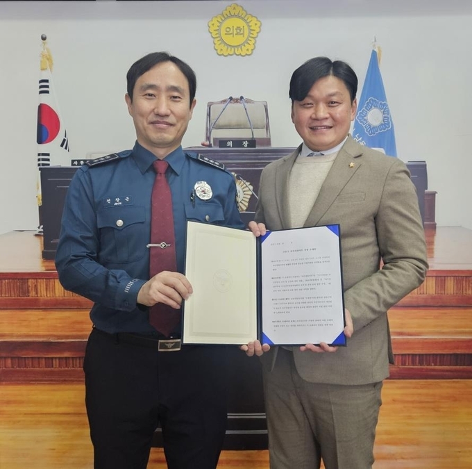 전창근 논현경찰서 범죄예방대응과장(왼쪽)과 김재남 남동구의원이 '자치경찰 사무 지원 조례안'을 들고 기념 사진을 찍고 있다. ( 사진 = 인천 논현경찰서 제공 )