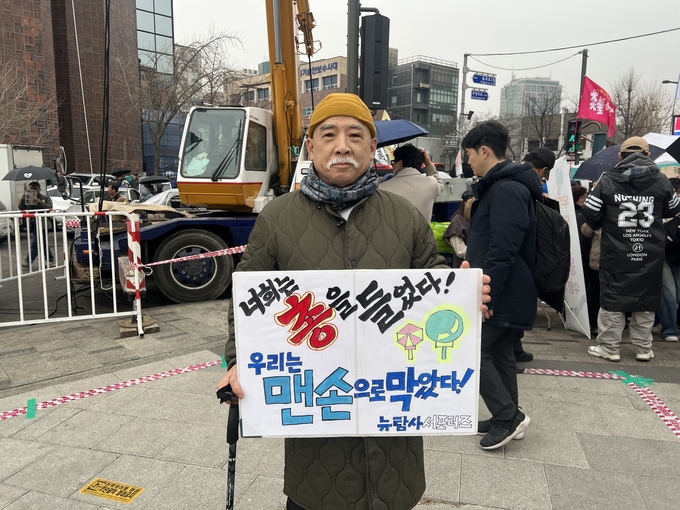 이하조 씨(68)가 손 팻말을 들고 집회에 함께하고 있다. (사진=장진 기자)