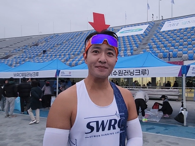 SWRC(수원러닝크루) 페이스메이커 정윤오(40) 씨가 2일 2025경기수원국제하프마라톤대회가 열린 수원종합운동장 주경기장 출발선 옆에서 빨간 머리띠를 쓰고 준비운동을 하고 있다. (사진=이유림 기자)