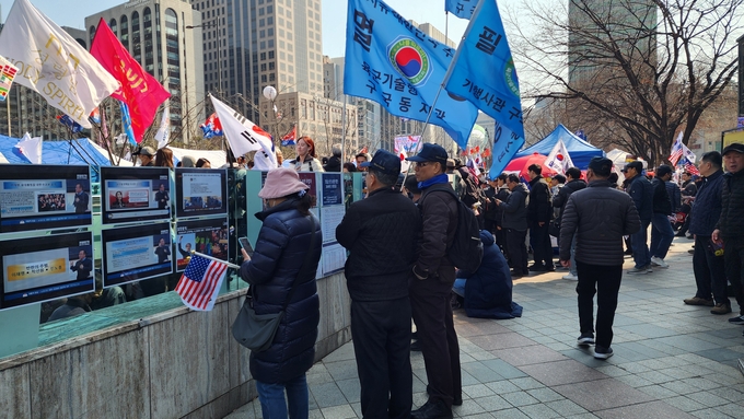  8일 서울 광화문 일대에 부착된 보수 단체의 홍보물을 읽고 있는 시민들. (사진=박진석 기자)