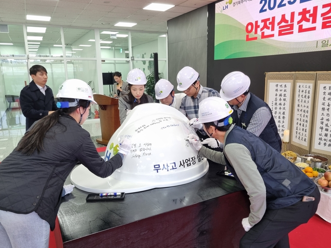 LH 경기북부지역 임직원들이 대형 안전모에 각자의 안전 다짐 문구를 적고 서명하고 있다. (사진=LH 제공)
