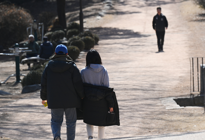  수원시 서장대에서 두꺼운 패딩을 입은 시민이 산책을 하다 따뜻해진 날씨에 외투를 반쯤 내려 입고 있다. (사진=옥지훈 기자)