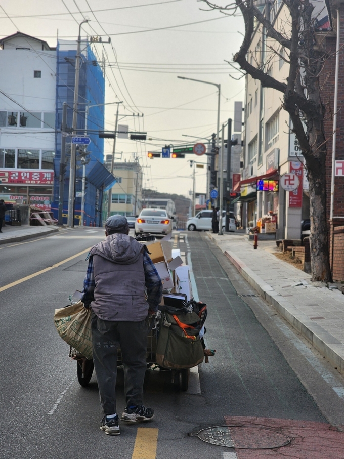 폐지 줍는 한 노인이 수례를 끌고 차도를 횡단하고 있다. (사진=천용남 기자)