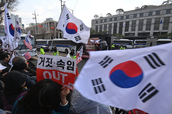윤석열 대통령 지지자들이 지난 16일 서울 종로구 헌법재판소 앞에서 태극기를 흔들고 있다. (사진=옥지훈 기자)