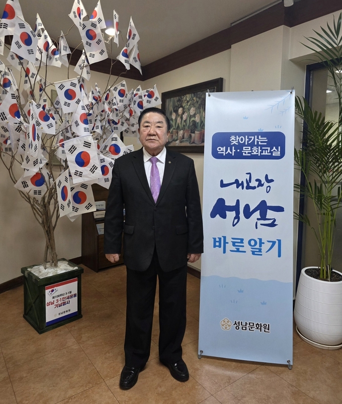 ‘내 고장 성남 바로 알기’ 교육 프로그램을 주관한 김대진 성남문화원장이 행사 홍보 배너 앞에서 기념촬영을 하고 있다. (사진=성남문화원 제공)