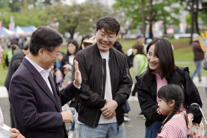 신상진 성남시장이 어린이날 행사장에서 시민 가족과 인사를 나누며 환하게 웃고 있다. 행사장은 많은 시민들로 북적이며 화기애애한 분위기를 자아냈다. (사진=성남시 제공)
