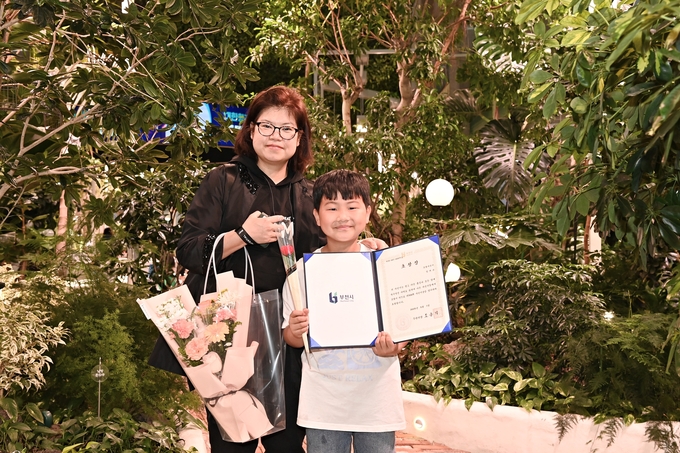정태운 군과 정군의 어머니가 모범 어린이 표창장을 들고 환하게 웃고 있다. (사진=부천시 제공)