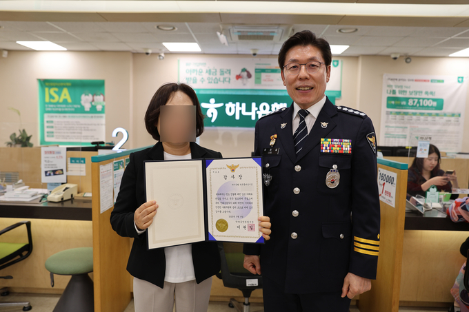 이원일(오른쪽) 안양동안경찰서장이 보이스피싱 피해를 막은 하나은행 직원에게 감사장을 준 뒤 기념촬영을 하고 있다. (사진=안양동안경찰서 제공)