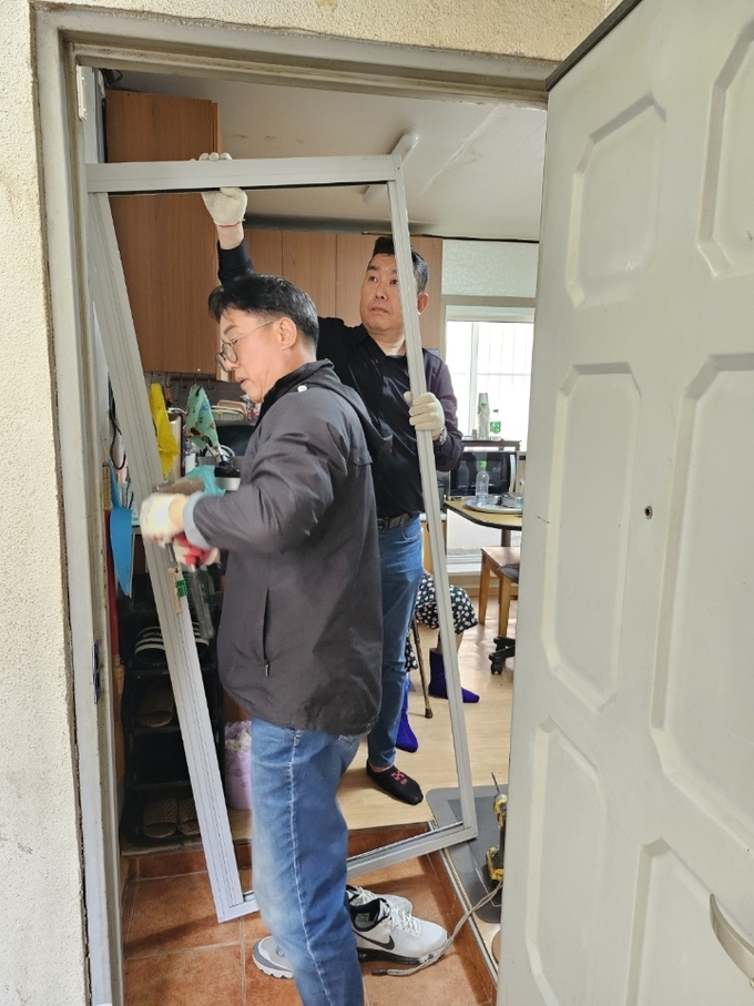 사우동 발전협의회 회원들이 독거 노인 가정을 방문 무료로 방충망을 교체하고 있다. (사진=김포시 사우동행정복지센터 제공)