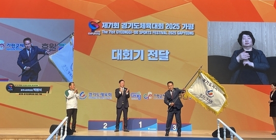 17일 가평체육관서 열린 '제71회 경기도체육대회 2025 가평' 폐회식에서 차기 대회 개최지 광주시의 박범식 체육회장(오른쪽)이 건네받은 대회기를 흔들고 있다. (사진=류초원 기자)