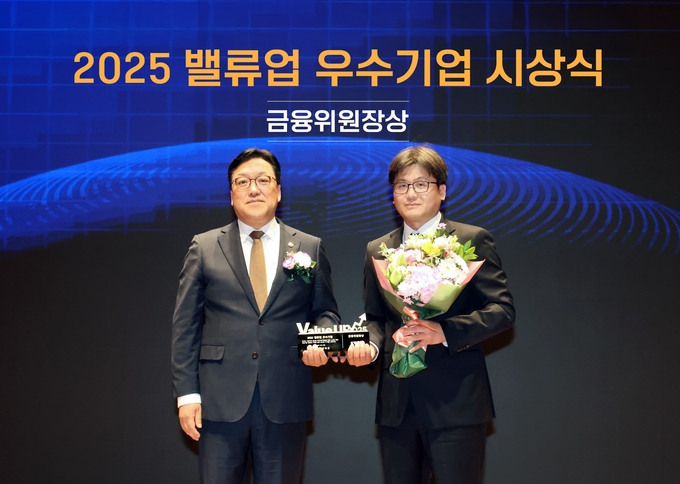 장석훈 삼양식품 경영지원본부장(오른쪽)과 김병환 금융위원회 위원장(왼쪽)이 기념 촬영을 하고 있다. (사진=삼양식품 제공)