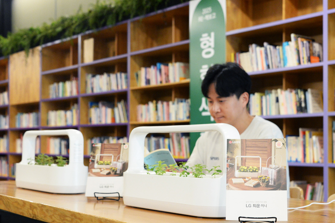 LG 틔운 미니를 활용해 조성된 내부 서가와 열람실 공간에서 독서하며 다양한 식물을 감상하는 모습. (사진=LG전자 제공)
