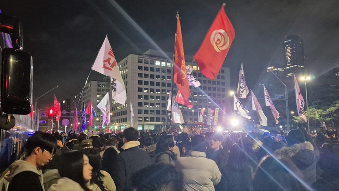 지난해 12월 4일 새벽 국회 앞에 모인 시민들이 깃발을 들고 비상계엄 해제를 촉구하고 있다. (사진=김한별 기자)