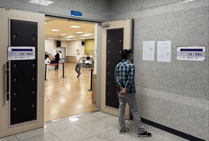 인천 서구 검단동의 행정복지센터에 설치된 투표소 앞에서 한 유권자가 선거 관련 홍보물을 보고 있다. ( 사진 = 이기준 기자 )