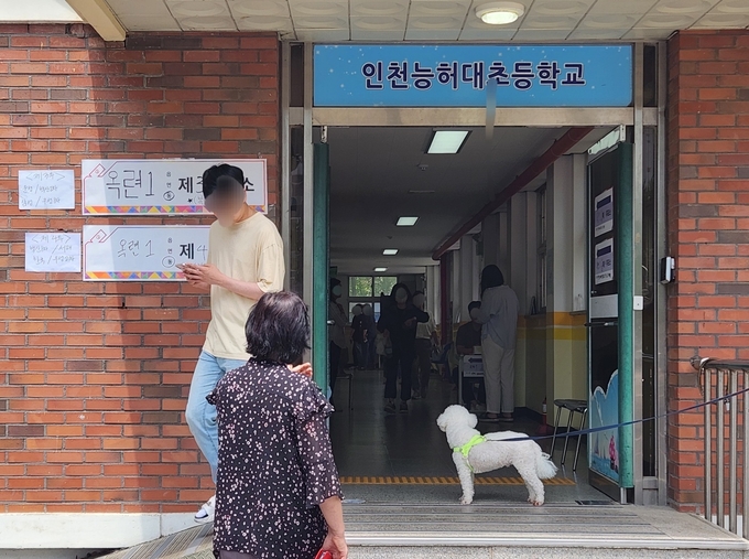 연수구 인천능허대초등학교 투표소 앞에 있는 개 한마리가 유권자들을 보고 있다. ( 사진 = 박지현 기자 )
