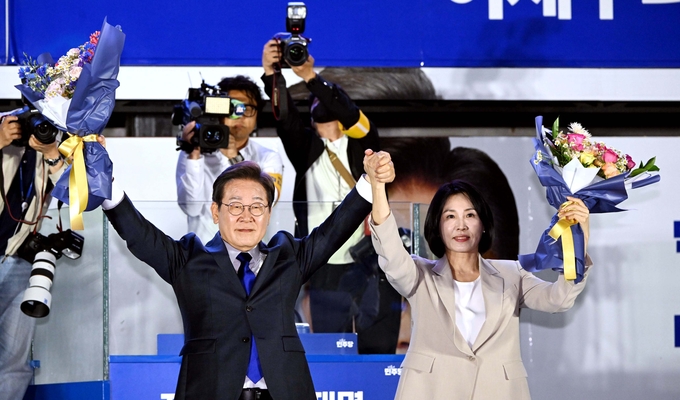 제21대 대통령 당선이 확실시되는 이재명 더불어민주당 대선 후보와 부인 김혜경 여사가 4일 서울 여의도 국회 인근에서 당 주최로 열린 국민개표방송 행사에 참석해 꽃다발을 받고서 시민들을 향해 두 팔을 들어 인사하고 있다. (사진=연합뉴스)
