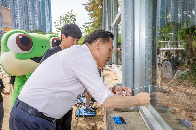 9일 이재준 수원시장이 송림초등학교 학생들과 함께 야생조류 충돌방지 테이프를 붙이고 있다. (사진=수원시 제공)