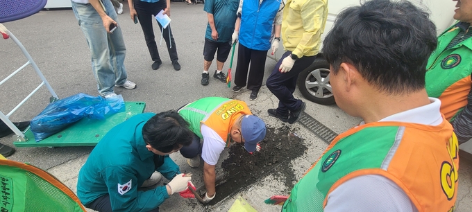 빗물받이 청소를 하고 있는 부천시 직원들과 자율방재단원들. (사진=부천시 제공)