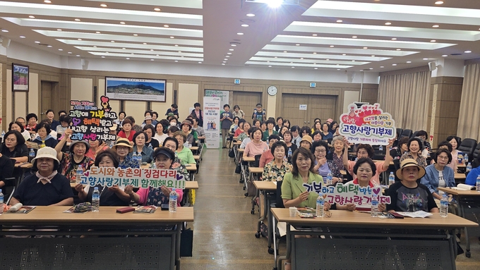 군포농협 노래교실 수강생들이 ‘고향사랑기부제’ 홍보 행사에 참여해 손팻말을 들고 기부 참여를 독려하고 있다. (사진=농협군포시지부 제공)