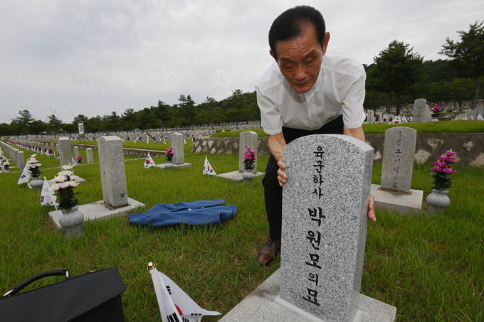 6.25 전쟁 발발 75주년을 하루 앞둔 24일 서울 동작구 국립현충원에서 박영진(70)씨가 참전 당시 25세의 나이로 순직한 백부인 故박원모 하사의 묘비를 어루만지고 있다.