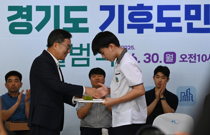 김동연 경기도지사가 30일 오전 시흥시 시흥에코센터에서 열린 경기도 기후도민총회 출범식에서 한 학생에게 기후도민 위촉장을 전달하고 있다.