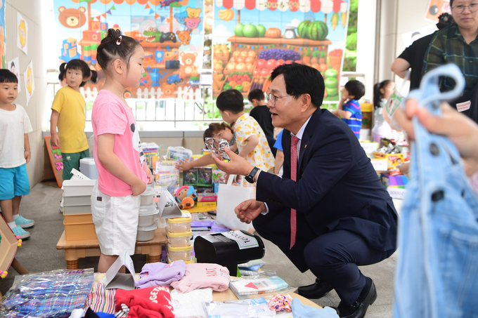 어린이집 바자회에 참여한 박용철 군수가 한 물건을 집어들며 아이와 대화하고 있다. ( 사진 = 강화군 제공 ) 