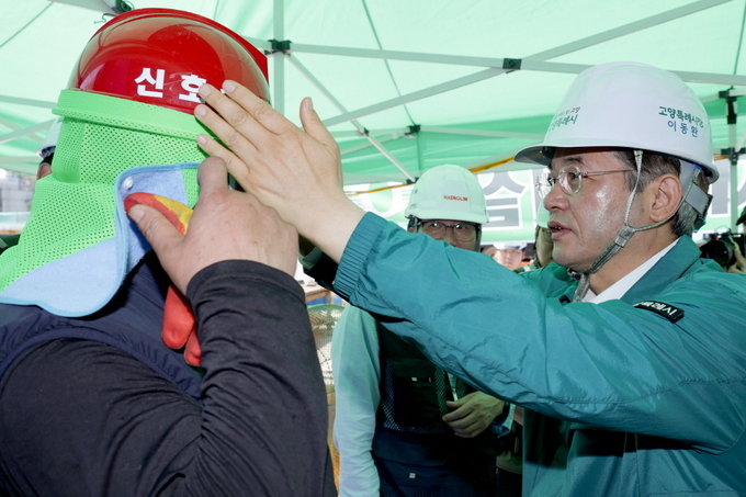 이동환 고양시장이 폭염이 계속 이어지자 공사현장을 찾아 근로자에게 차광막이 달린 안전모를 씌어주고 있다. (사진=고양시 제공)<br>
