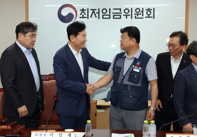 최저임금위원회 사용자위원 운영위원인 류기정 한국경영자총협회 전무(왼쪽)와 근로자위원 운영위원인 류기섭 한국노총 사무총장이 10일 정부세종청사에서 열린 제12차 전원회의에서 내년 최저임금을 시간당 1만320원으로 17년 만에 합의로 결정한 뒤 악수하고 있다. 왼쪽은 이인재 위원장, 오른쪽은 이명로 중소기업중앙회 인력정책본부장. (사진=연합뉴스)