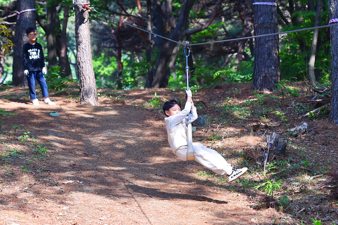 죽화초등학교 학생들이 숲놀이터에서 짚라인을 타고 있다. (사진=죽화초등학교 제공)