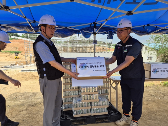강성혁(왼쪽) 경기주택도시공사(GH) 도시활성화본부장이 14일 광명학온 공공주택지구 건설현장에서 현장 근로자에게 보냉장구와 이온음료 등을 전달하고 있다. (사진=GH 제공)