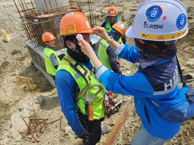 DL이앤씨 현장 안전보건관리자가 근로자의 체온을 측정하고 건강상태를 확인하고 있다. (사진=DL이앤씨 제공)