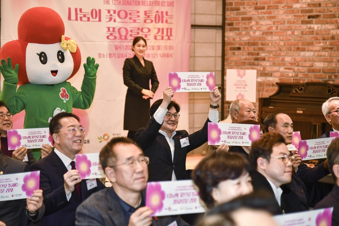 김포시 복지재단이 나눔문화를 조성하기 위해 추진한 62일간의 나눔릴레이에 동참한 김병수 시장을 비롯해 각 기관장들이 나눔 페이지를 들고 기념식에 환호하고 있다. (사진=김포복지재단 제공)