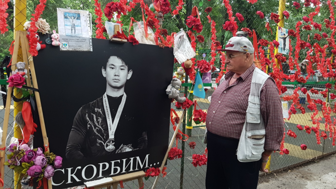 사고 현장에 마련된 고인의 추모공간에 걸려 있는 데니스의 사진을 한 시민이 바라보고 있다. (사진=김상욱 알마티고려문화원장 제공)