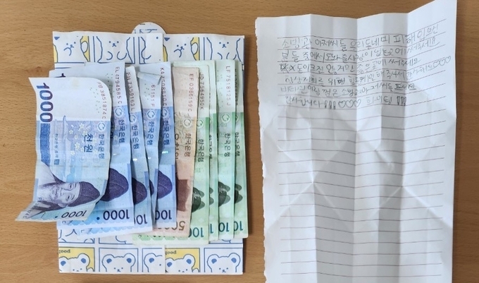 가평소방청사 현관 앞 포장된 상자 안에 있었던 5만원 상당의 현금과 1만3천원 어치의 간식류, 그리고 손글씨로 적인 편지 한장. (사진=가평소방서 제공)