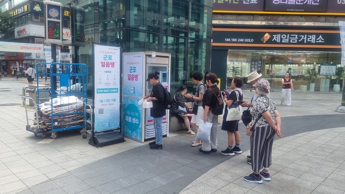 AI 무인 냉장고 ‘군포 얼음땡’을 이용하기 위해 줄을 선 시민들. 한여름 폭염 속 시원한 생수 한 병이 더위를 식혀주고 있다. (사진=군포시 제공)