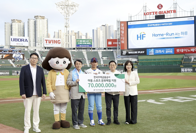 지난 27일 한국주택금융공사는 부산광역시 동래구에 위치한 사직야구장에서 유호재 한국주택금융공사 이사, 한국주택금융공사 캐릭터 주하, 김경환 한국주택금융공사 사장, 박지훈 장학생, 이홍렬 초록우산 홍보대사와 이수경 초록우산 부산지역본부장(왼쪽부터)이 기념촬영을 하고 있다. (사진=한국주택금융공사 제공)
