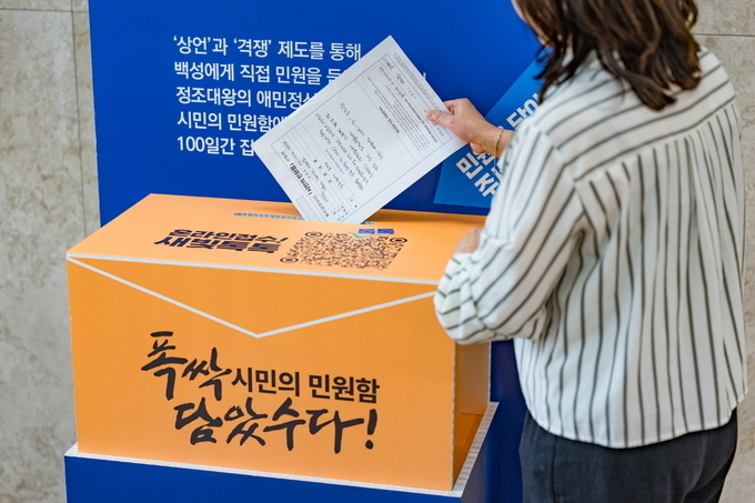 한 시민이 ‘폭싹 담았수다! 시민의 민원함 신청서’를 작성한 뒤 수원시청에 설치된 민원함에 넣고 있다. (사진=수원시 제공)