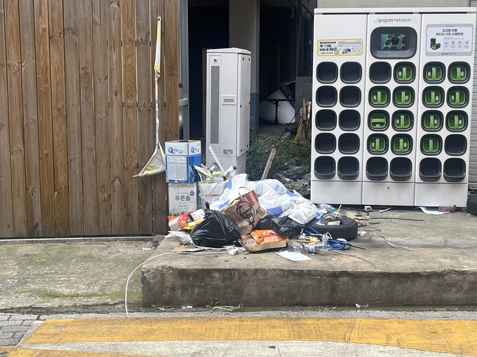  9시 오전 수원역 로데오거리에 종량제 봉투에서 터져 나온 쓰레기가 널브러져 있다. 뒤쪽 나무 벽면에는 '쓰레기 무단투기 금지' 현수막이 찢긴 채로 걸려있다. (사진=안규용 기자)