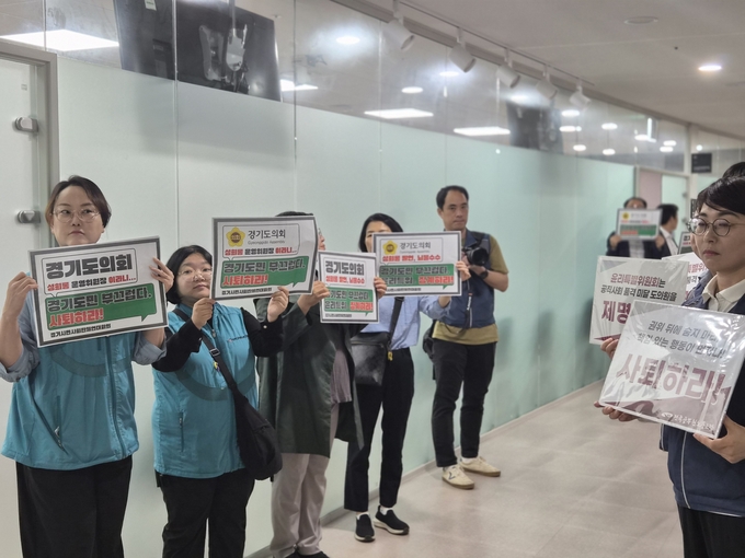 18일 경기도의회 운영위원회 회의실 앞에서 경기시민사회단체연대회의 관계자들이 양우식(국힘·비례) 경기도의회 운영위원장을 규탄하는 내용의 피켓을 들고 있다. (사진=이유림 기자)