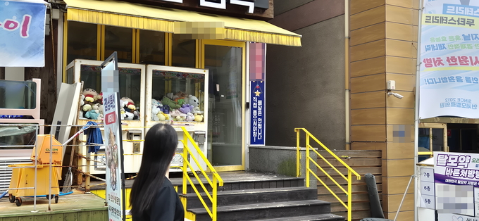 압류 관련 등기우편물이 부착된 문 닫힌 매장 옆으로 한 시민이 걸어가고 있다. ( 사진 = 지우현 기자 )