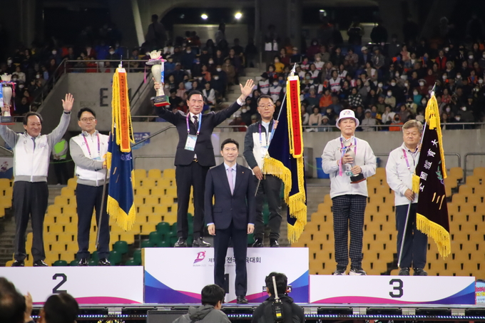 23일 부산아시아드경기장에서 진행된 '제106회 전국체육대회' 폐회식에서 종합우승을 차지한 경기도선수단 이원성 단장(경기도체육회장)과 김택수 총감독(경기도체육회 사무처장)이 우승 트로피와 우승기를 들고 기뻐하고 있다. (사진=경기도체육회 제공)