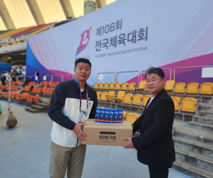 전인철 건국건설(주) 부산지사장이  경기도육상연맹 조현민 사무국장에게 호관원크림을 전달하고 있다.(사진=문정만 회장 제공)