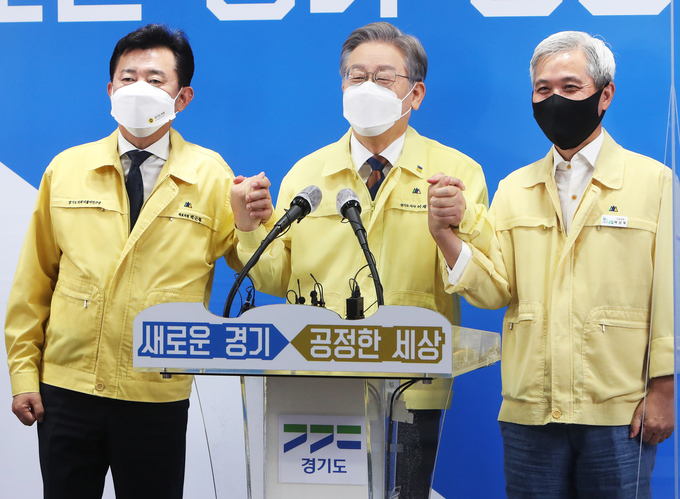 이재명 경기도지사가 15일 오후 경기도 수원시 경기도청 브리핑룸에서 경기도의회 더불어민주당 박근철 대표의원(왼쪽), 곽상욱 경기도시장군수협의회 회장(오른쪽)과 제3차 경기도 재난기본소득 지급 관련 기자회견을 마친 후 손을 맞잡고 있다. (사진=연합뉴스) 