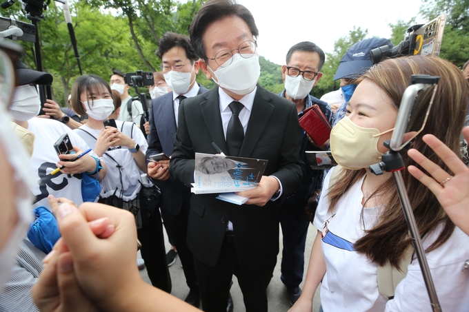 전당대회 당대표에 출마한 더불어민주당 이재명 의원이 23일 오전 경남 김해시 진영읍 봉하마을 고(故) 노무현 전 대통령 묘역을 참배한 후 지지자들에게 사인을 해주고 있다. (사진=연합뉴스 제공)