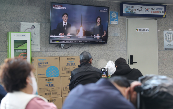 3일 울릉도를 방문한 관광객들이 TV에서 나오는 북한 미사일 관련 뉴스를 시청하고 있다. (사진=연합뉴스 제공)