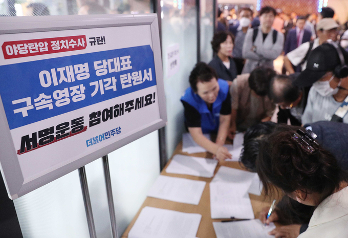 지난 24일 진교훈 더불어민주당 강서구청장 후보자 선거사무소 개소식에서 민주당 지지자들이 이재명 대표 구속영장 기각 탄원서에 서명하고 있다. (사진=연합뉴스)