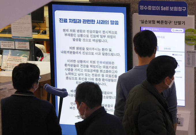 인천의 한 대학병원에 붙은 진료 차질 사과문을 환자들과 보호자들이 보고 있다. ( 사진 = 연합뉴스 제공 )