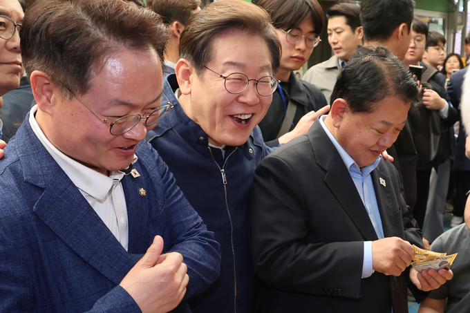 이재명 더불어민주당 대선 후보가 ‘골목골목 경청투어’ 접경지역 방문 이틀째인 2일 강원도 인제군 원통전통시장에서 건어물 가게에 들러 황태채를 맛본 뒤 김병주(오른쪽)·허영 의원에게 구입을 권하고 있다. (사진=연합뉴스)