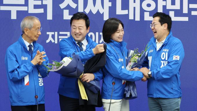 더불어민주당 박찬대 대표 직무대행 겸 원내대표(오른쪽)와 윤여준 총괄선대위원장(왼쪽)이 26일 서울 여의도 당사에서 열린 중앙선거대책위원회의에서 허은아(오른쪽 두번째), 김용남 전 의원에게 선거운동복을 입혀 준 뒤 손잡고 있다. (사진=연합뉴스)